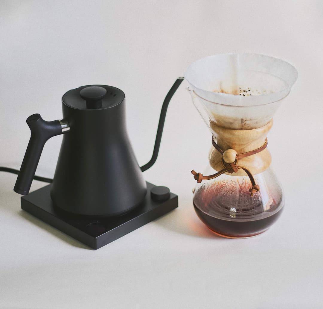 Goose necked kettle beside a Chemex with a filter with ground coffee.